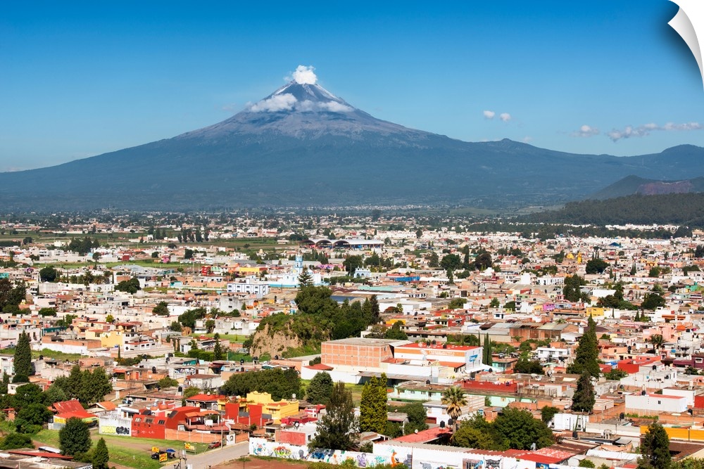 Aerial photograph of the Popocatepetl Volcano in Puebla, Mexico, with a bird's eye view of the city in the foreground. Fro...
