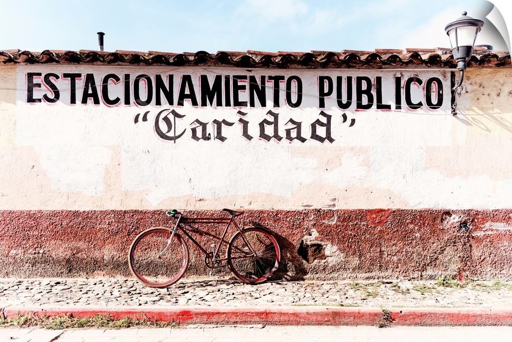 Photograph of a red bicycle parked in front of a wall with the phrase "Estacionamiento publico" (Public Parking) spray pai...
