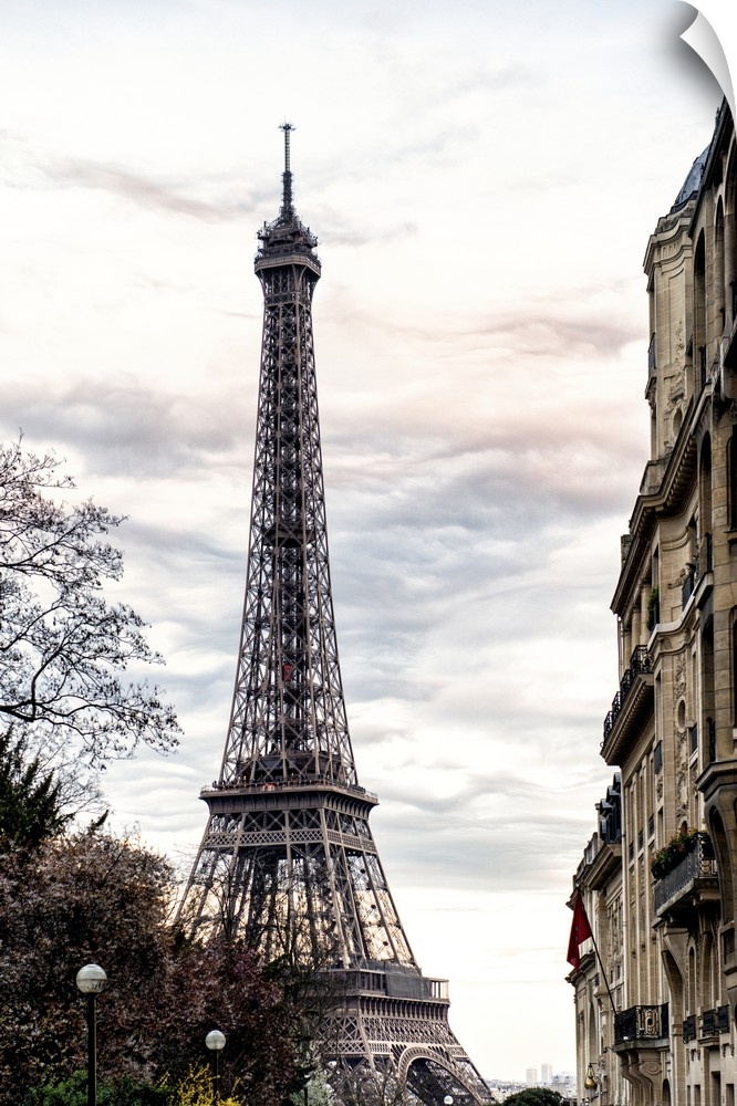 View of the famous Eiffel Tower monument in Paris, France, against an overcast sky.