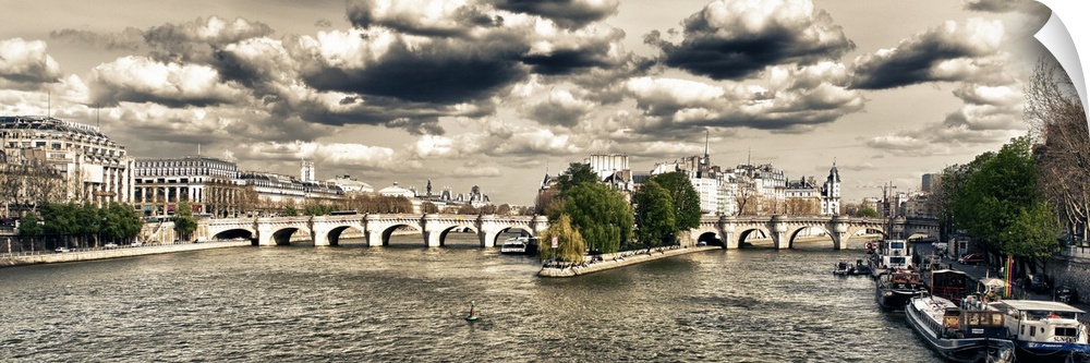 Panoramic view of an arched bridge over the River Seine under dramatic clouds.
