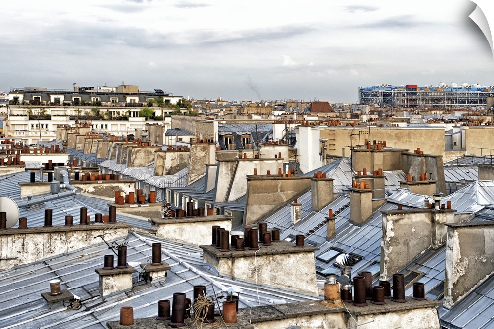 Panoramic image of the windows and grey roofs of a row of Parisian buildings with the Paris skyline in the distance.