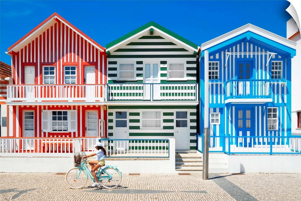 These are three facades of colorful houses with stripes with a cyclist in turquoise bike in Costa Nova Beach, Portugal.