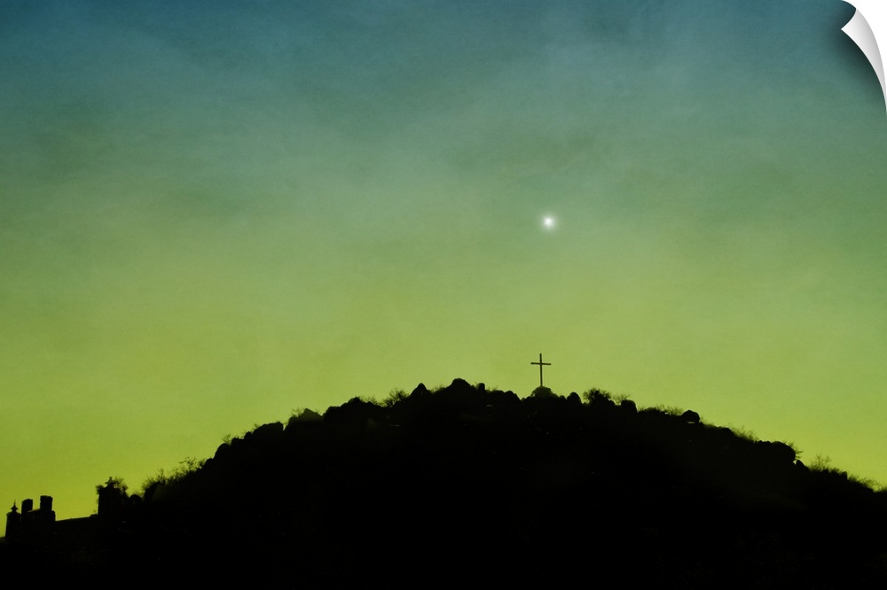 The silhouette of a cross on top of a hill.