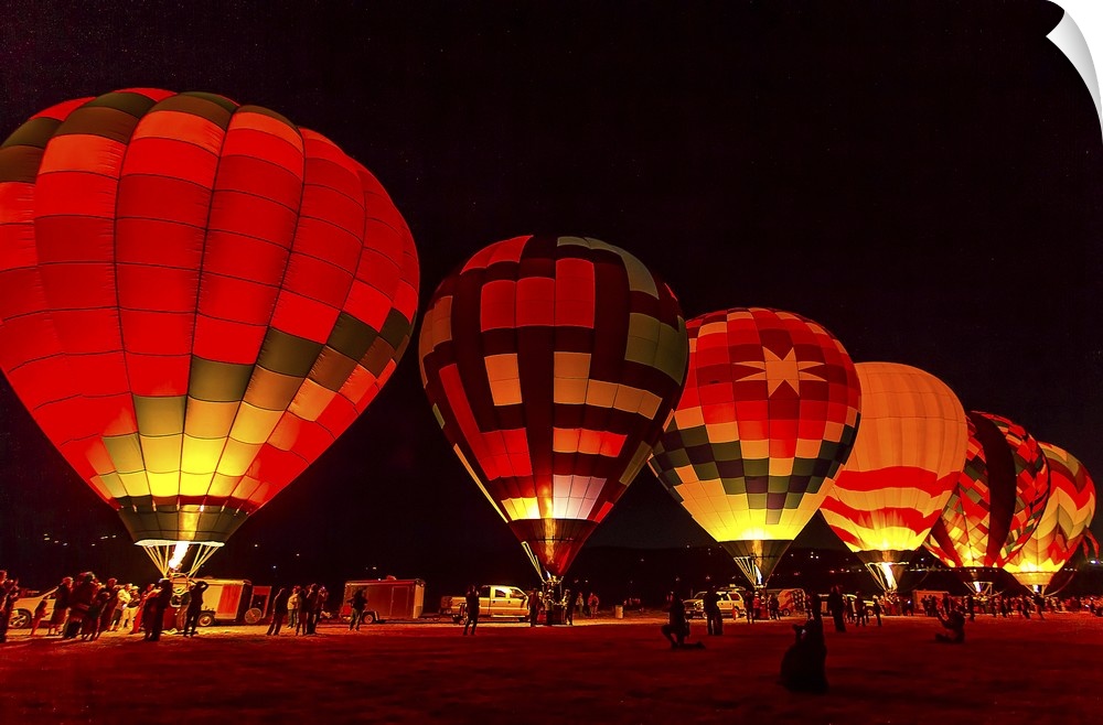 A row of hot air balloons glowing from the light inside, ready to take off at dawn.
