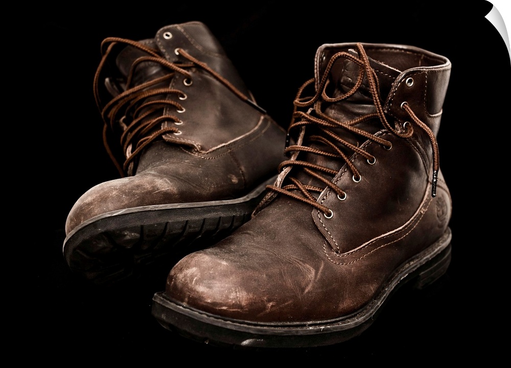 A pair of well-worn brown boots with laces.