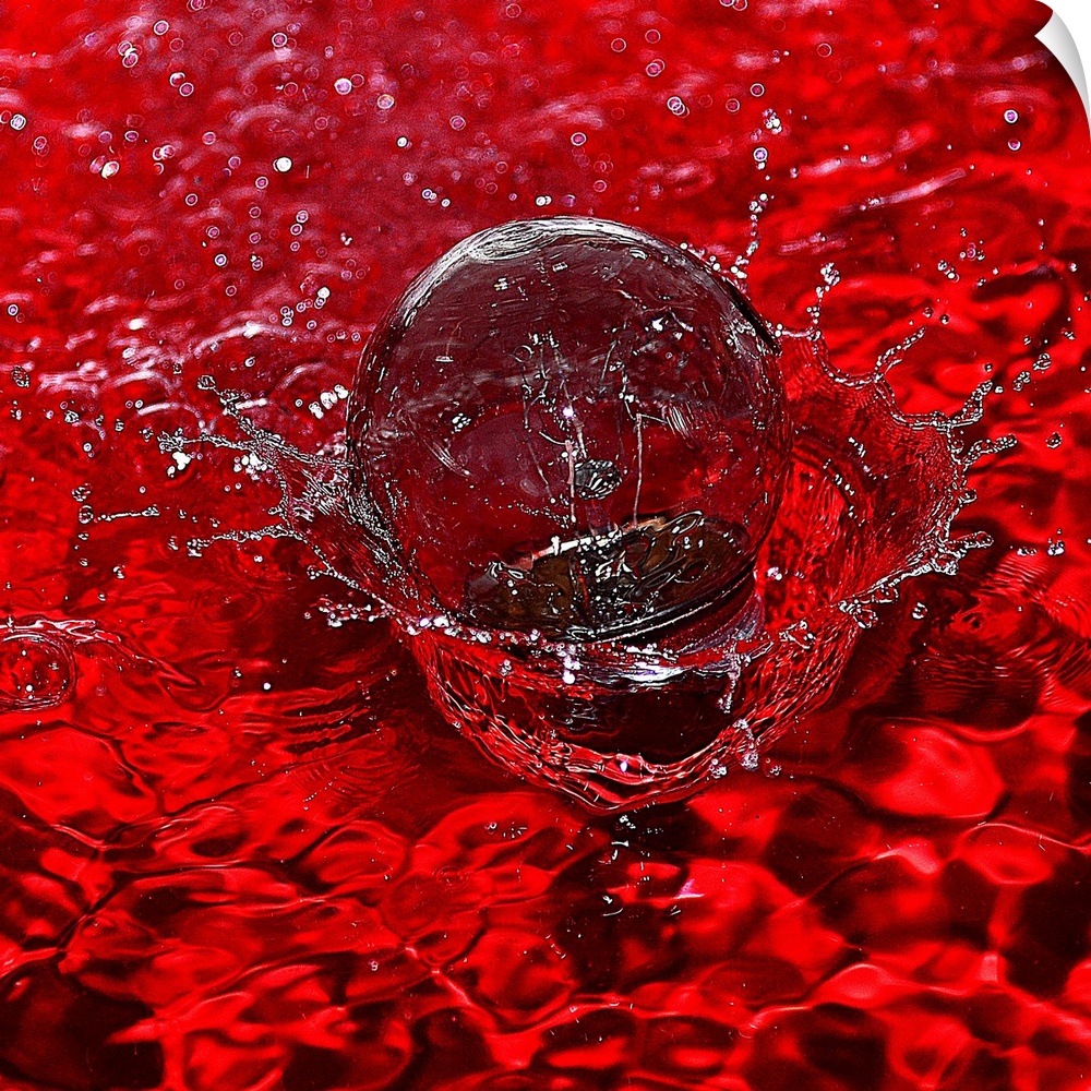 Macro photograph of a water drop splashing into water reflecting bright red.