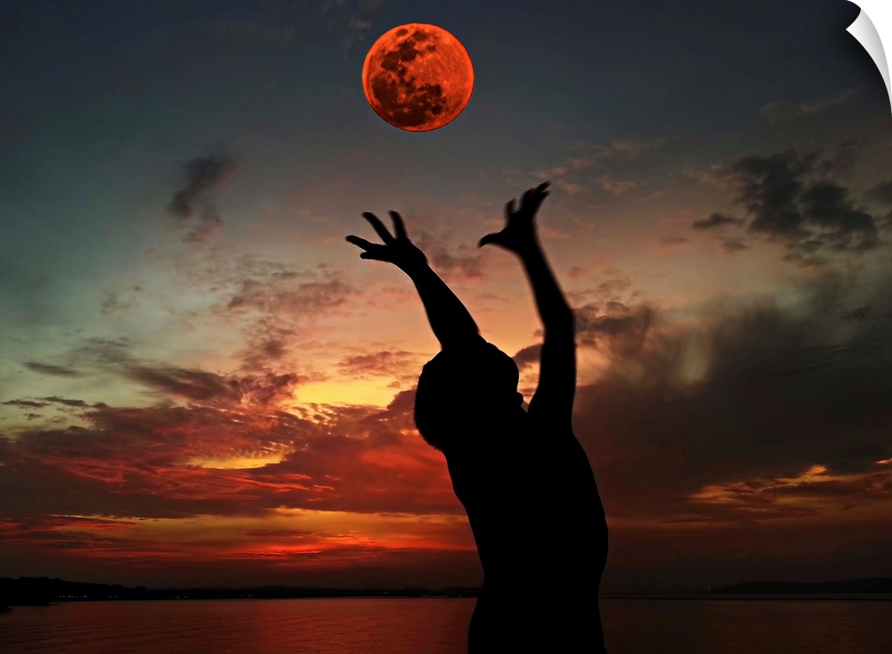 Silhouette of a person with their arms outstretched towards the red moon in the sky.