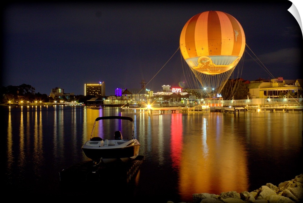 A hot air balloon glowing against the night sky over a lake.