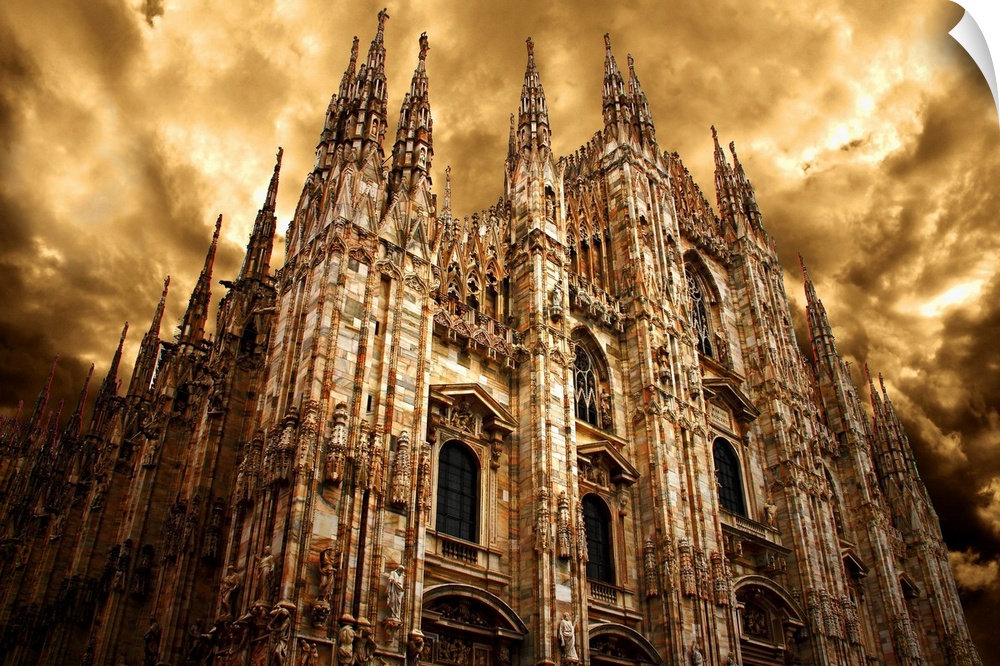 Milan Cathedral under a cloudy sky in golden light.