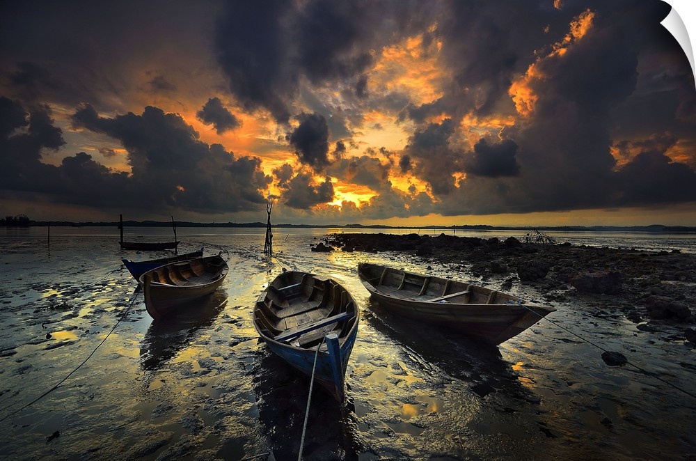 Row boats sitting in still water under dramatic clouds at sunset.