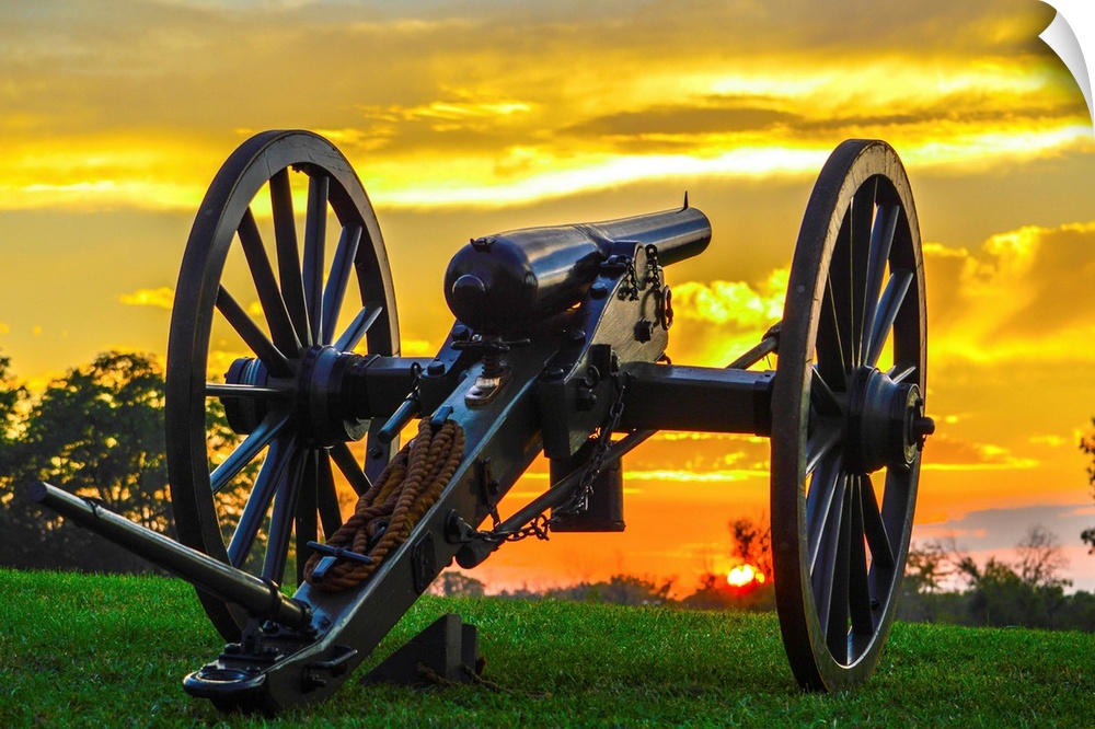 A historical cannon on an old battlefield at sunset.