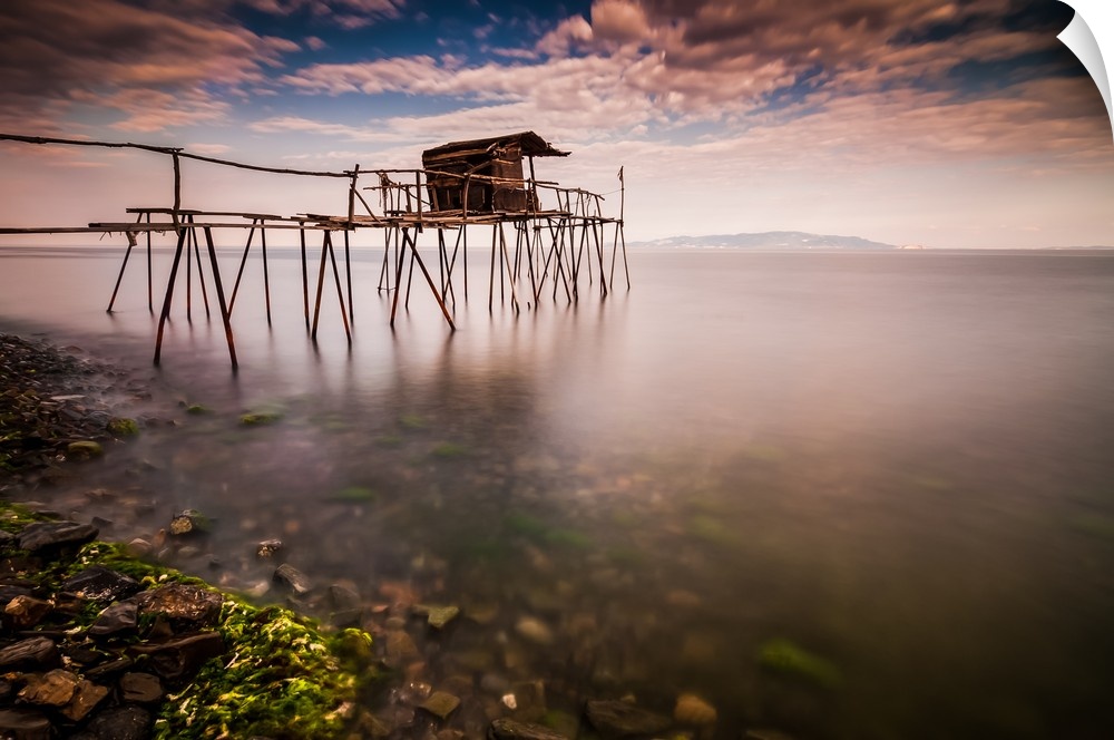 Fishing hut on tall stilts in the still waters of the ocean.