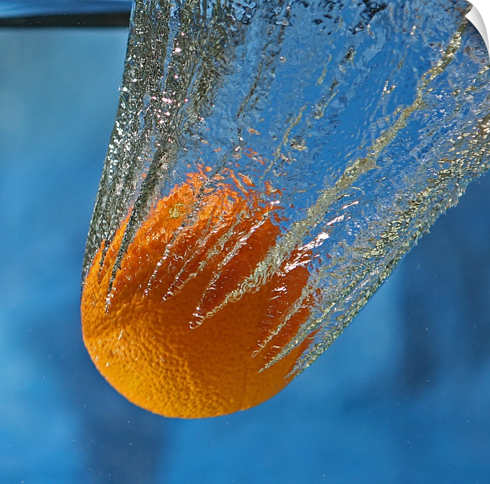 An orange splashing into a tank of clear water.