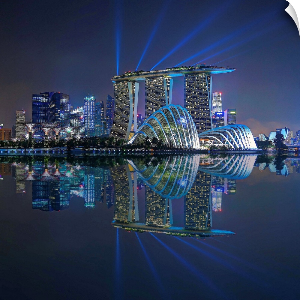 Singapore skyline lit up in neon lights with spot lights stretching out toward the sky.