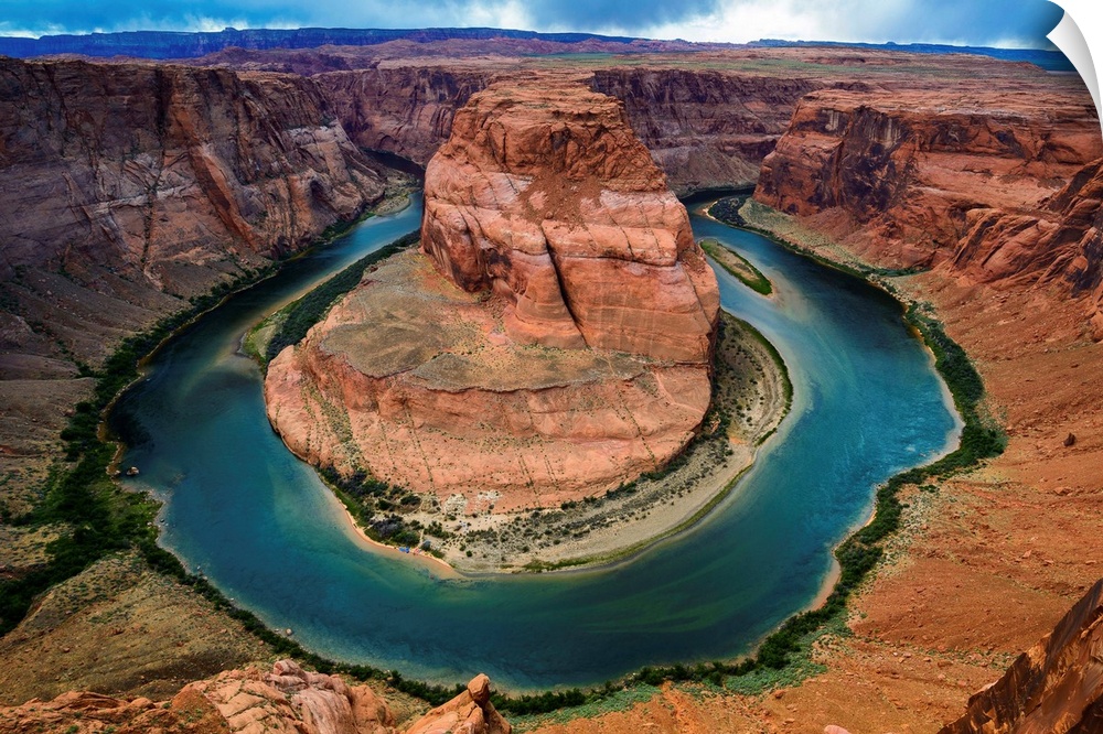 Horseshoe Bend section of the Colorado River with partly cloudy skies and rain in the distance.