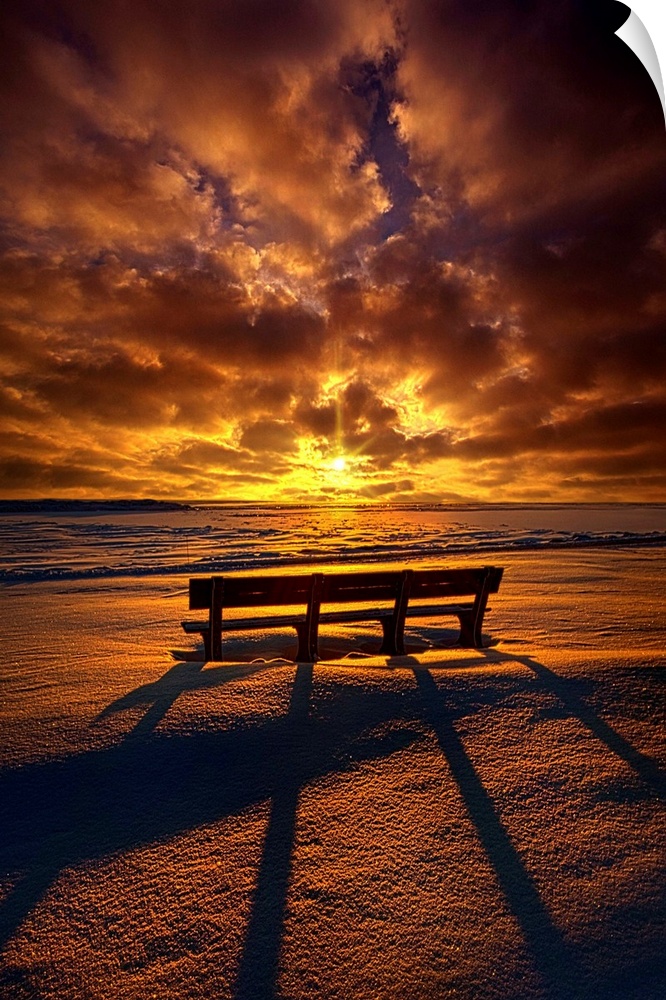 Long shadows cast by a bench at sunset under a cloudy sky.