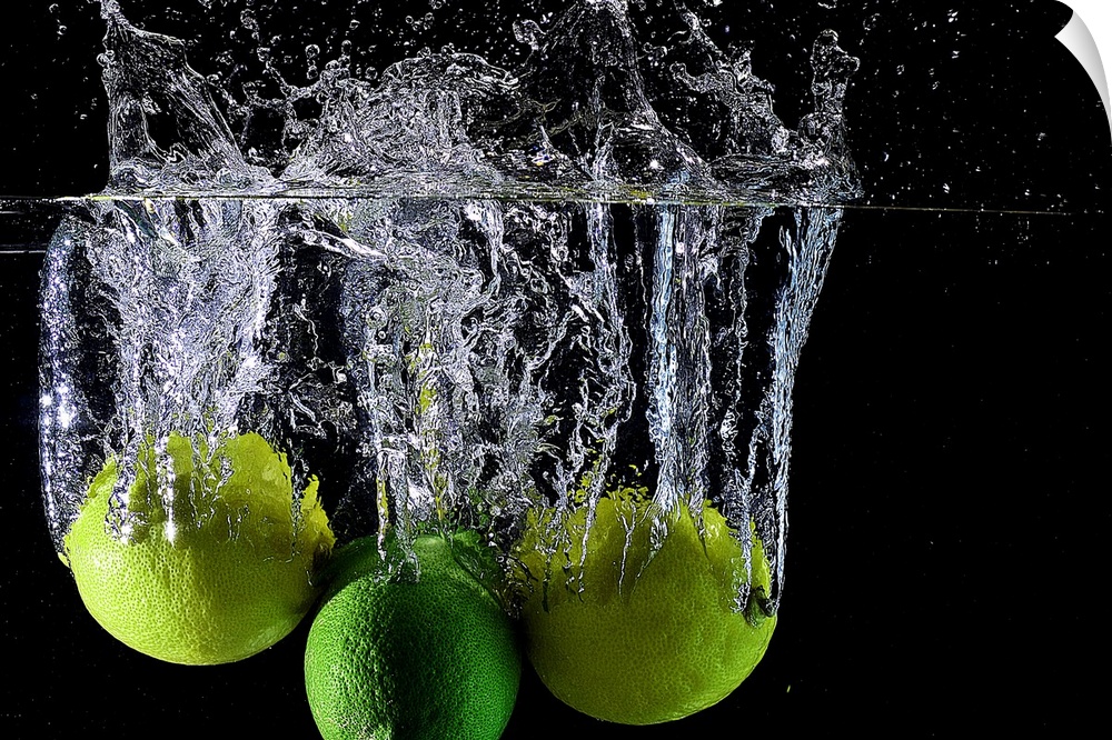 Lemons and limes splashing into clear water.