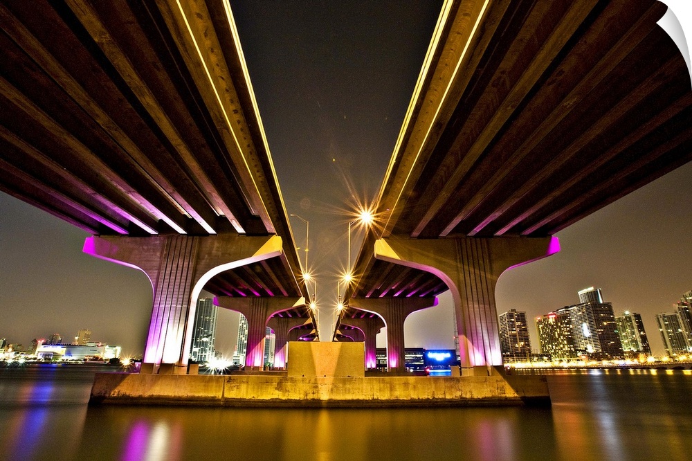 Dynamic photograph of two overpasses leading to Miami, glowing from neon lights.