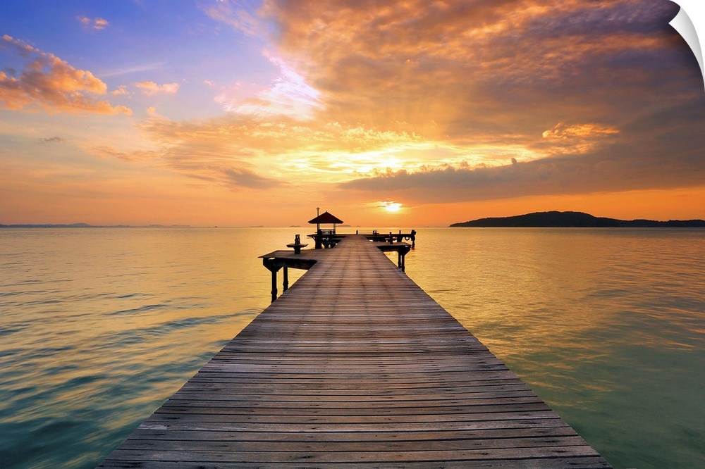 A wooden pier stretching into the ocean at sunrise, Maldives.