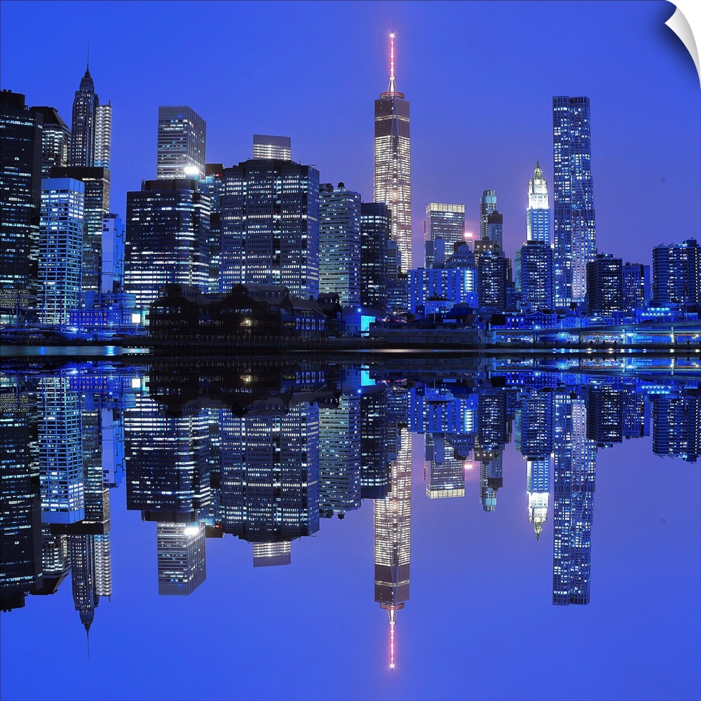New York City skyline at night, reflected in the bay below.