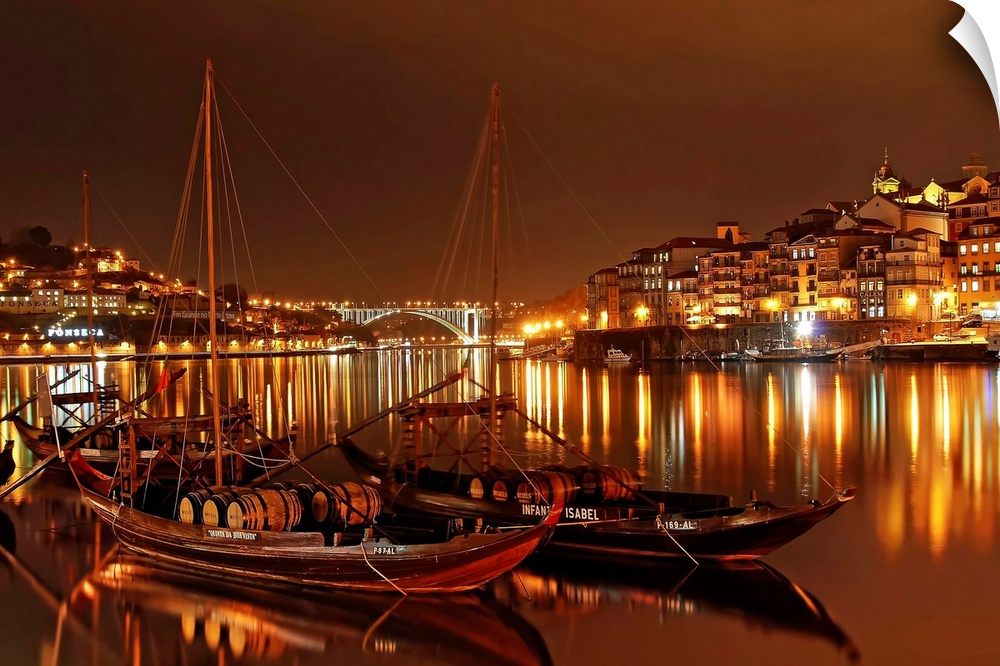 Boats in the River Douro in Porto illuminated with city lights at night.