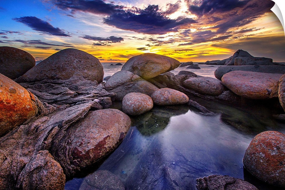 Beautiful sunset colors and dramatic clouds over a rocky beach.