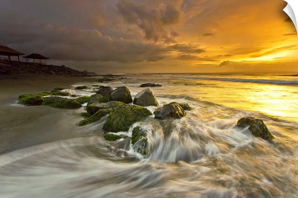 Beautiful sunset over low tidewater rushing over rocks on the beach.