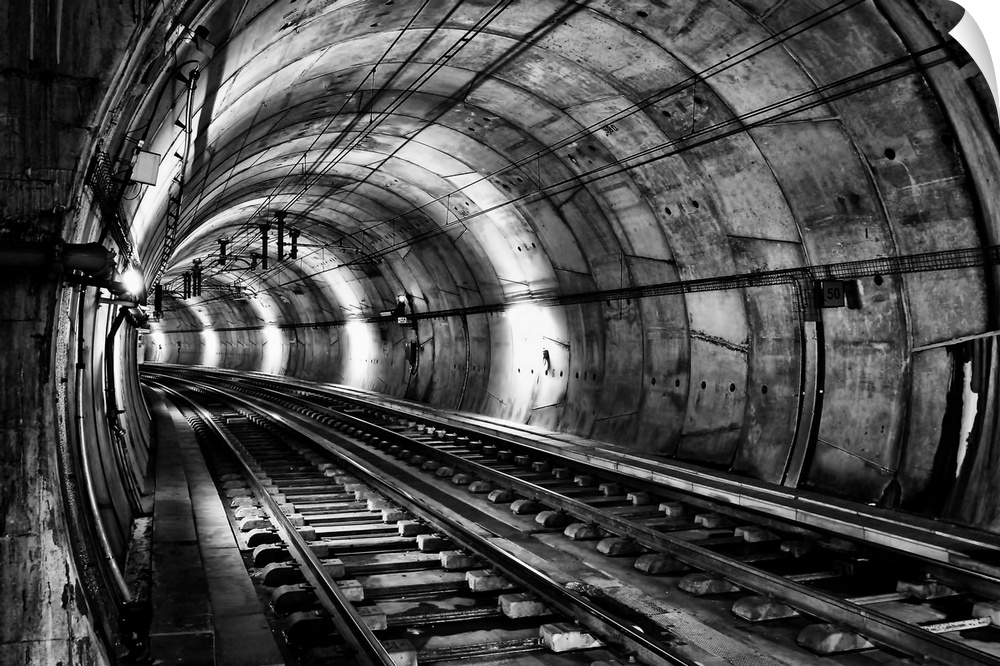 Train tracks in an underground tunnel, in black and white.