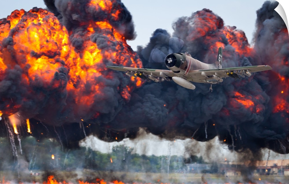 A military plane flies away from large fiery smoke clouds created by explosions.