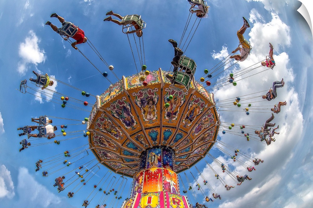 An amusement park ride with people on swings, under a blue sky.