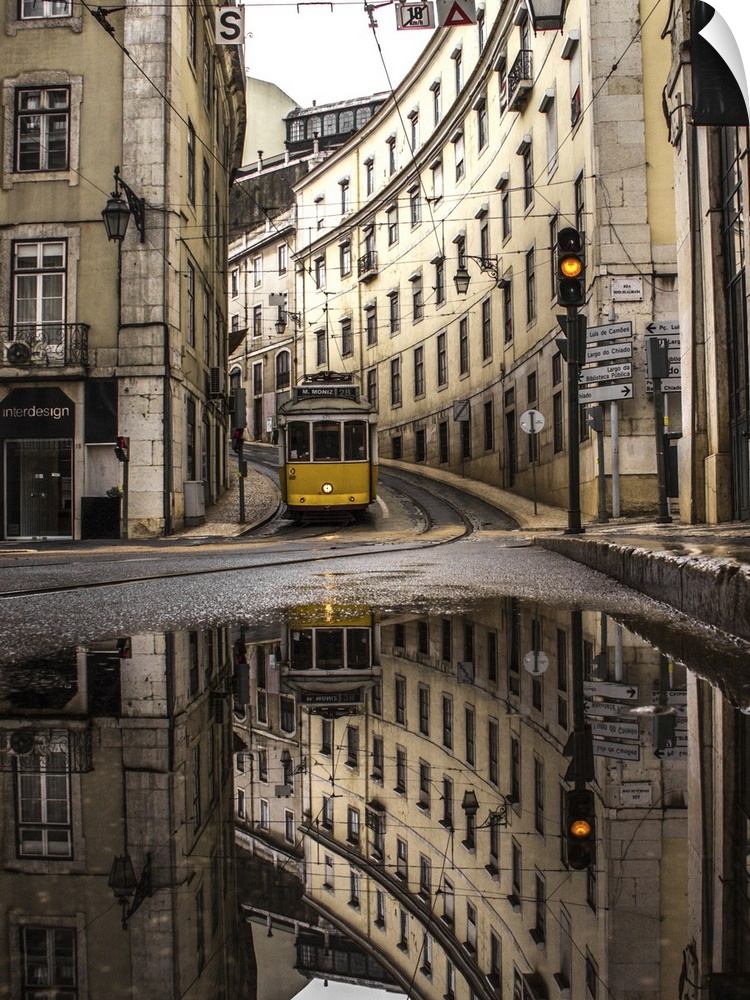 An old street of Lisbon with a yellow train coming. Yellow traffic light. The street view reflects in a puddle.