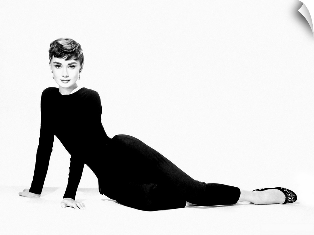 A large piece of artwork in black and white of Audrey Hepburn sitting on her hip and both arms stretched out to support he...