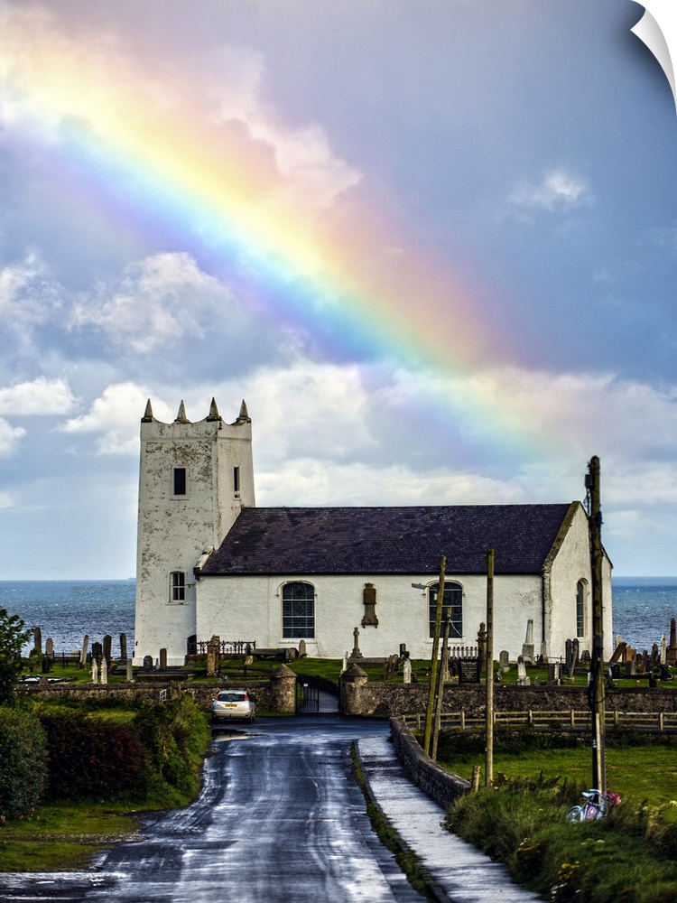 Photograph of Ballintoy Parish Church with a beautiful rainbow behind it over the ocean, at Ballintoy Harbour near Bushmil...