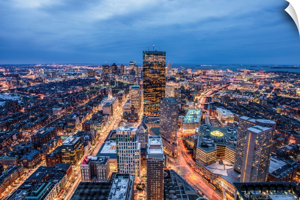 View from a skyscraper of tall buildings in Boston glowing at night.