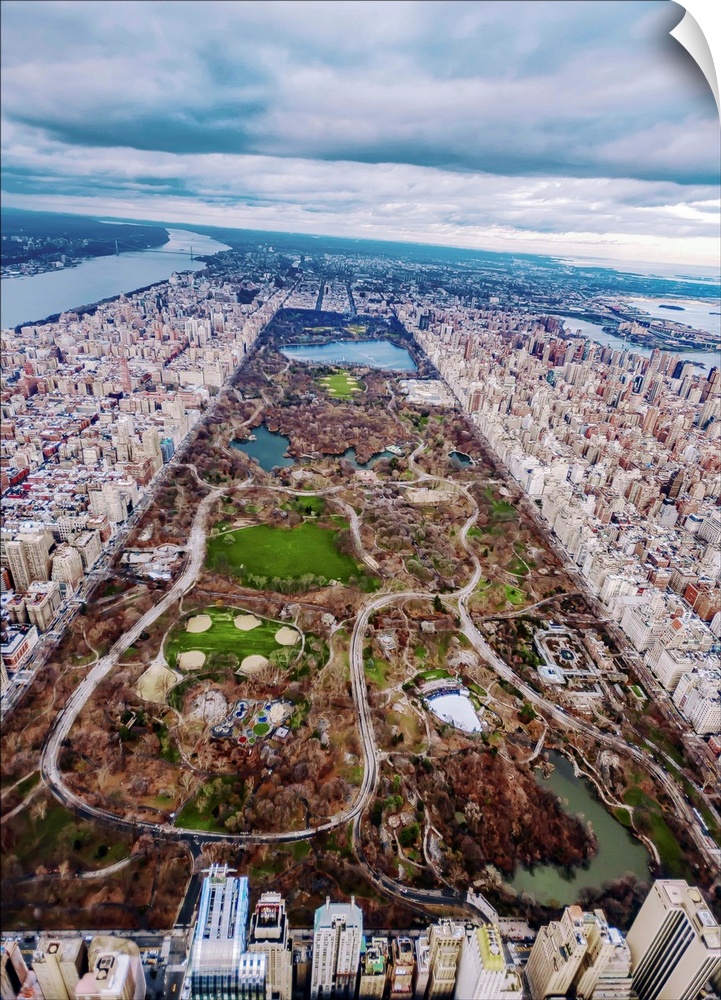 Aerial view of Central Park in New York City, surrounded by skyscrapers, under a cloudy sky.
