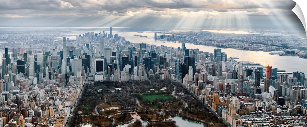 Panoramic view of Central Park in New York City, surrounded by skyscrapers, under a cloudy sky.