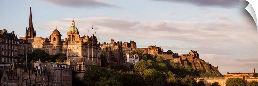 Panoramic photograph of part of the city of Edinburgh with the castle in the background, at golden hour.
