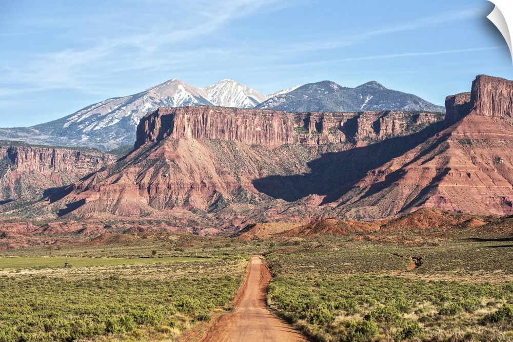 A dirt road leading towards the sandstaone cliffs and La Sal Mountains in Arches National Park, Moab, Utah.