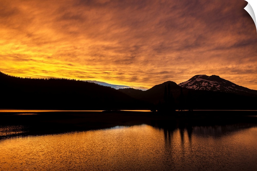View of a dramatic sunset with vibrant oranges against a silhouette of Deschutes National Forest in Oregon.