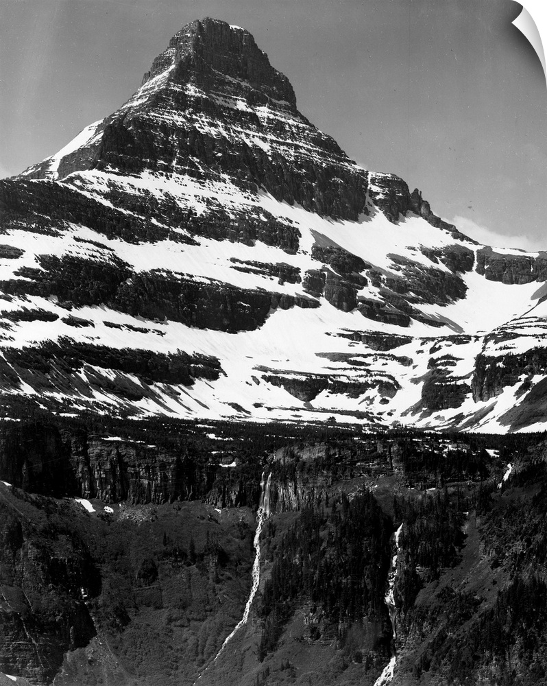 In Glacier National Park, vertical, full view of snow covered mountain, including area below timberline.