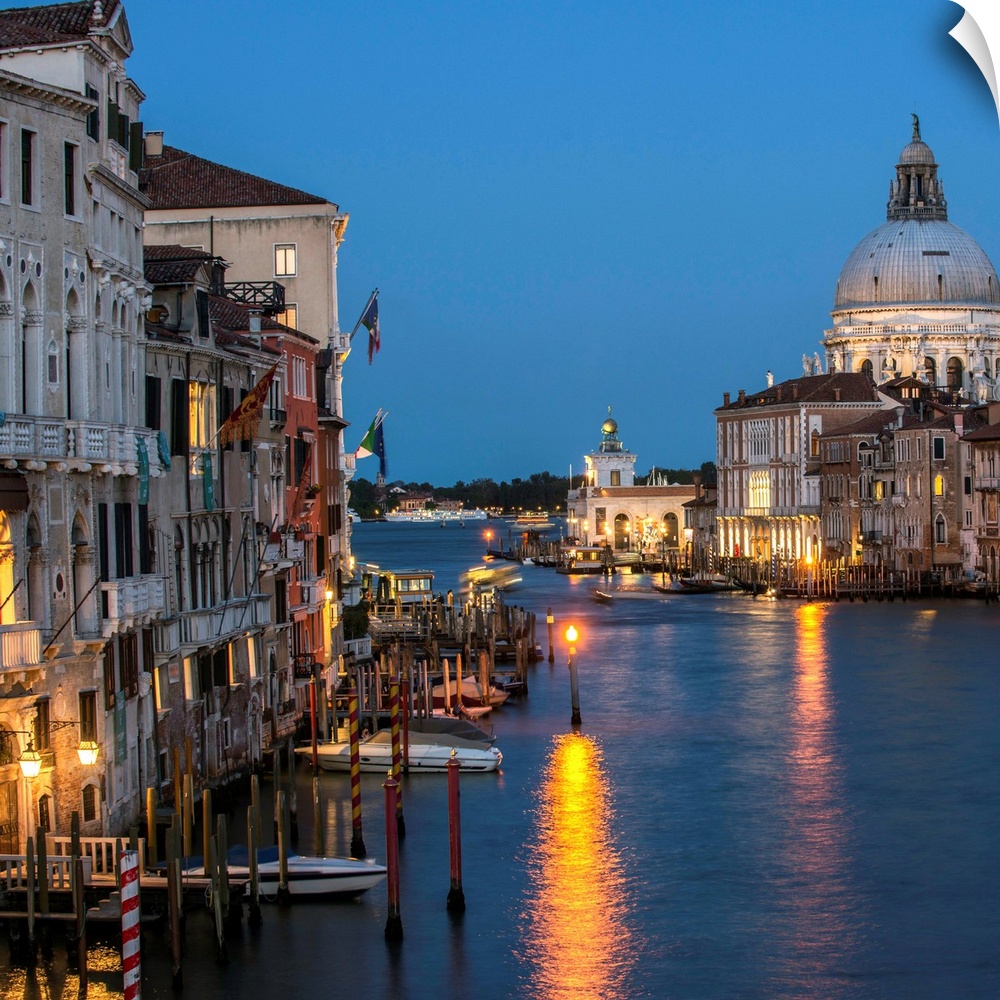 Square photograph of Grand Canal lit up at night with the Santa Maria della Salute in the background.