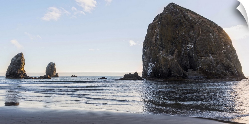 Panoramic photograph of Haystack Rock at Cannon Beach with blue skies.