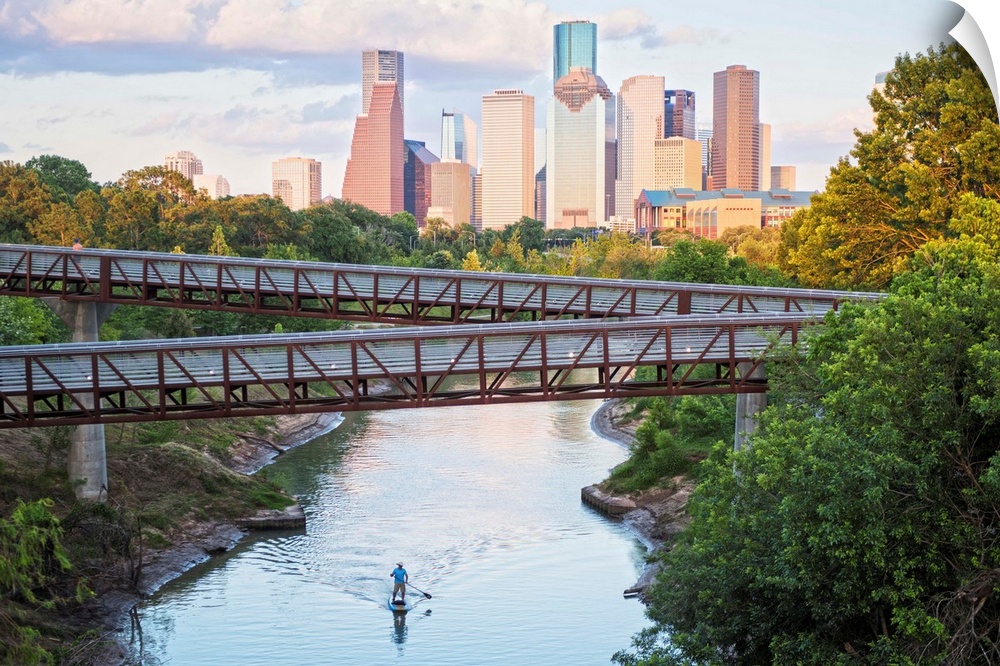 Photograph of the Houston TX skyline in the distance with the  Rosemont pedestrian bridge in the foreground over the Buffa...