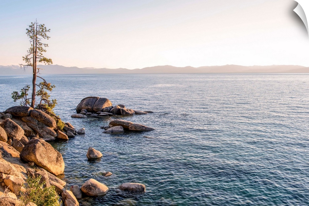 View of Lake Tahoe's rocky shore with mountain landscape in the background in California and Nevada.
