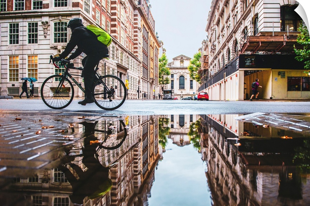 Photograph of a biker reflecting into a puddle in London, England.