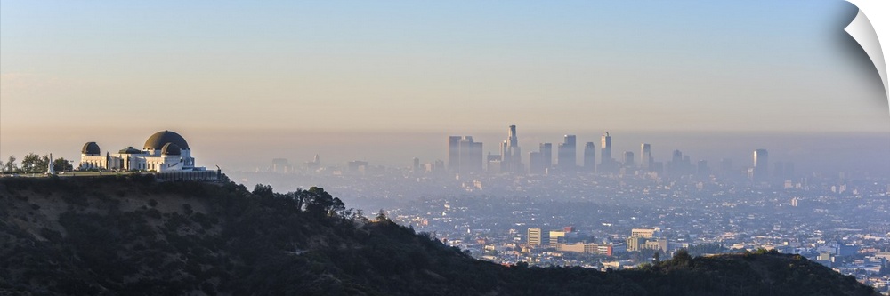 Panoramic photograph of the hazy Los Angeles skyline with Griffith Observatory on the left in the foreground.