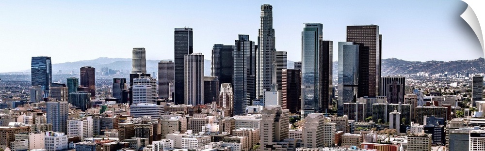 Panoramic photograph of skyscrapers and surrounding buildings of the Los Angeles skyline under a blue sky, California.