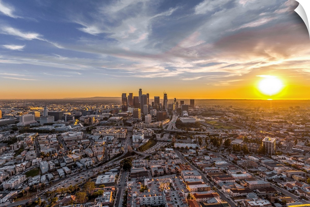 The setting sun visible behind the skyscrapers in the Los Angeles skyline, California.