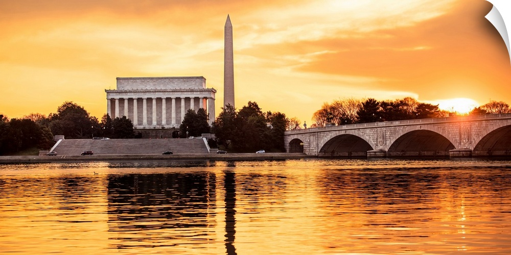 The Lincoln Memorial and Washington Monument seen from the Potomac River with orange clouds at dusk.
