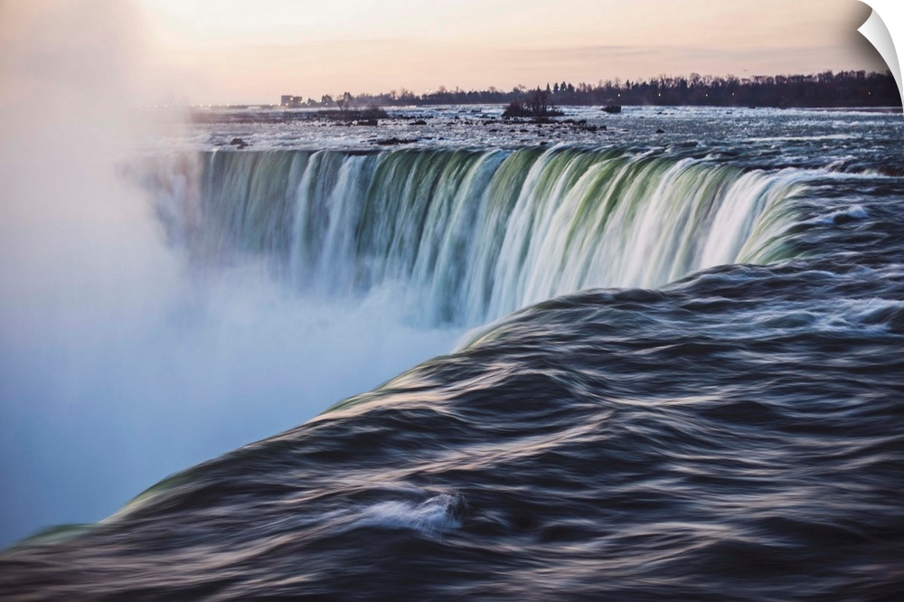 Water cascades down at Horseshoe Falls while dramatic mist ascents to meet the rising sun.